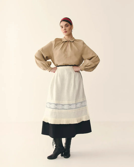Woman in traditional Ukrainian clothing with beige blouse, embroidered apron, long black skirt and boots