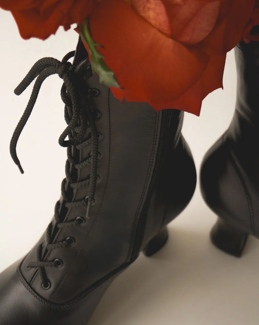 Black leather lace-up boots with low heels and red flower accents, traditional style footwear
