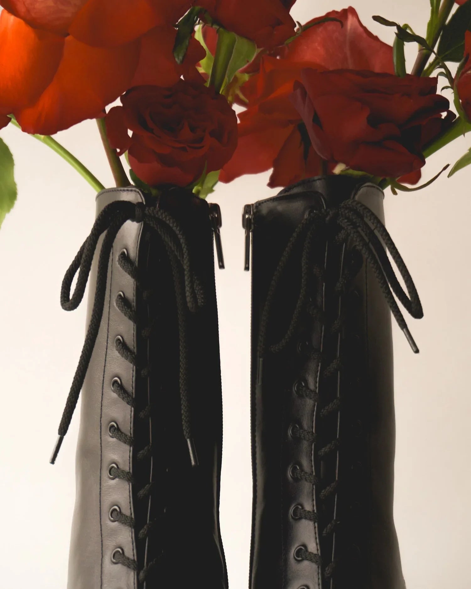 Black lace-up leather boots with red roses inside, minimalist fashion concept