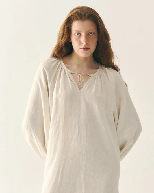 Woman in natural linen Ukrainian traditional blouse with tie-neck and full sleeves