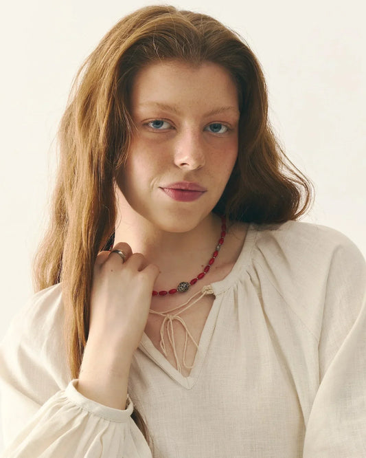 Woman in traditional Ukrainian linen blouse with red beaded necklace, close-up portrait